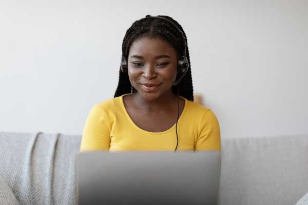 A woman wearing a headset is on a laptop computer. 