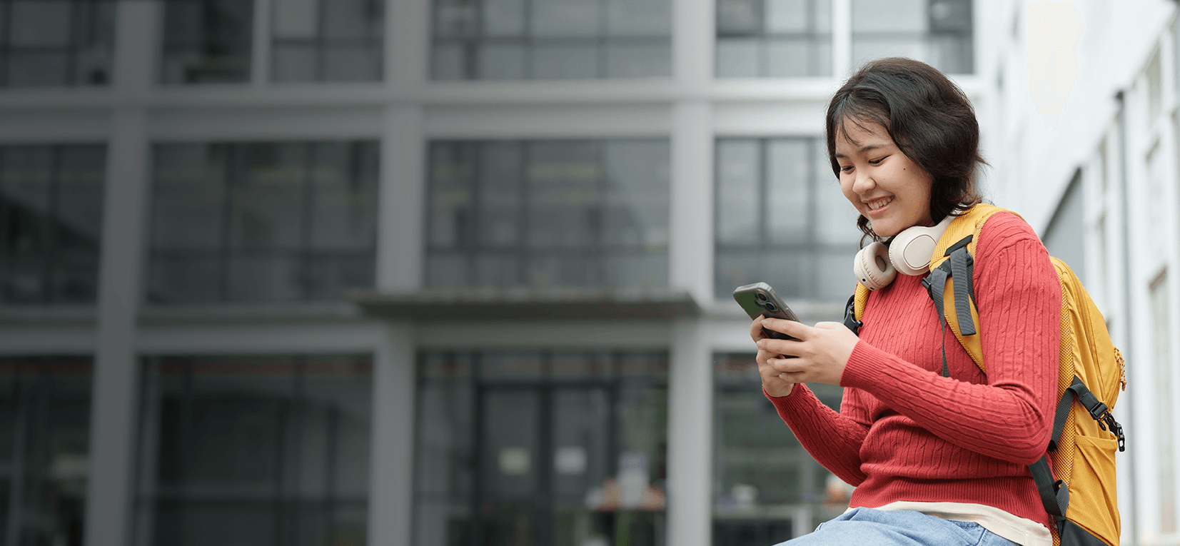 A young woman is on her phone with a happy expression.