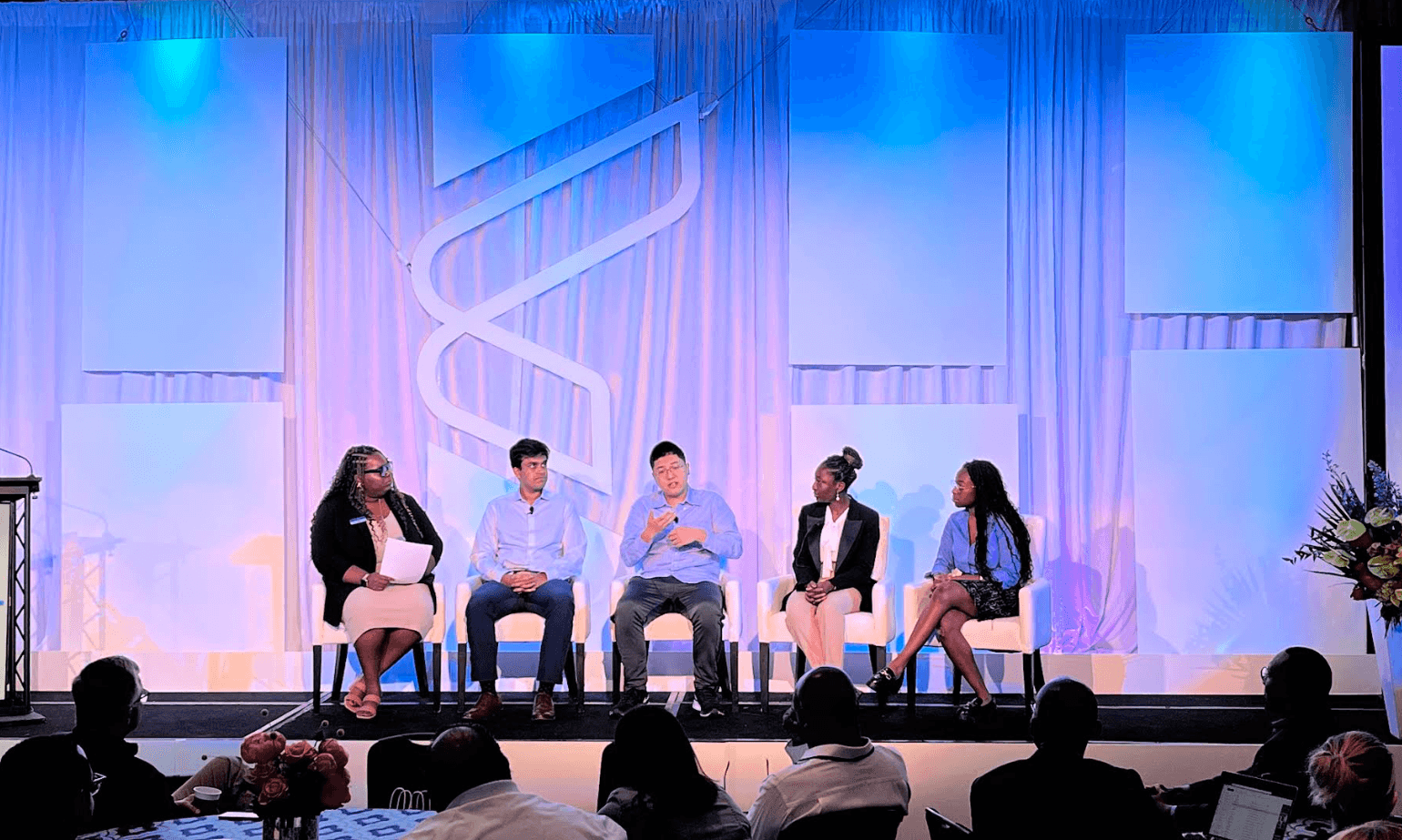 A panel of students is on stage answering questions from an audience. 