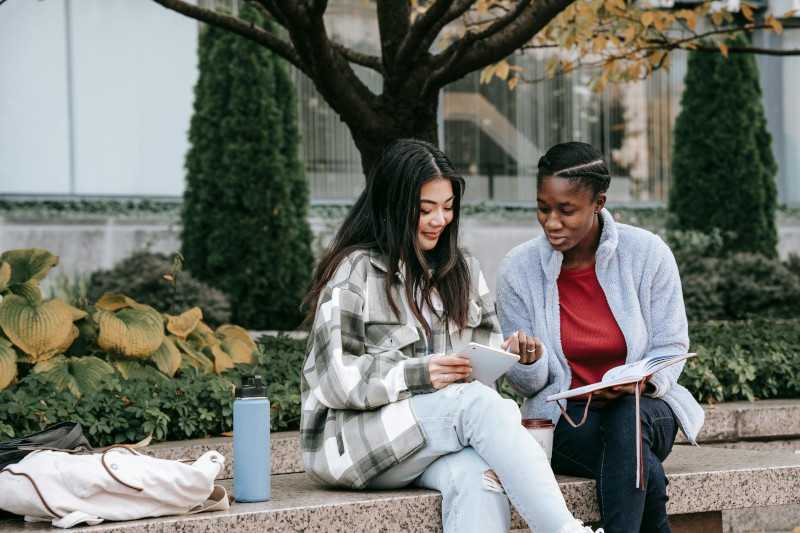 Two female students are looking at a tablet having a discussion. 