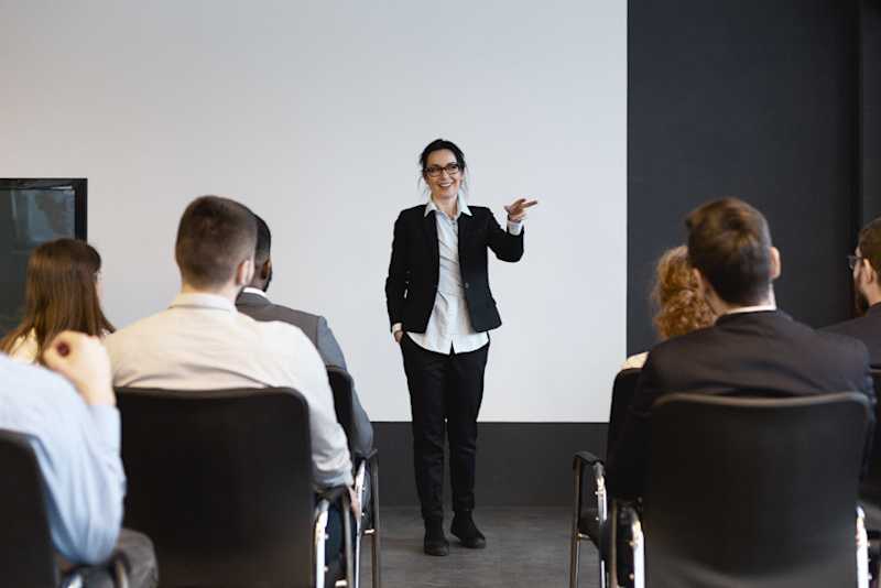 A presenter is speaking to a group of people. 