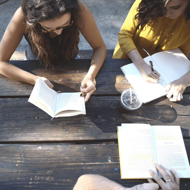 A view from above of people working/reading at a picnic table. 