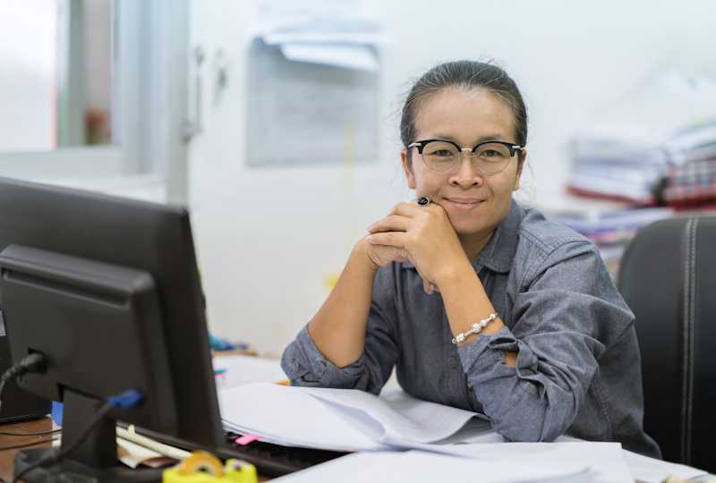 A woman is sitting at a desk with paperwork. 