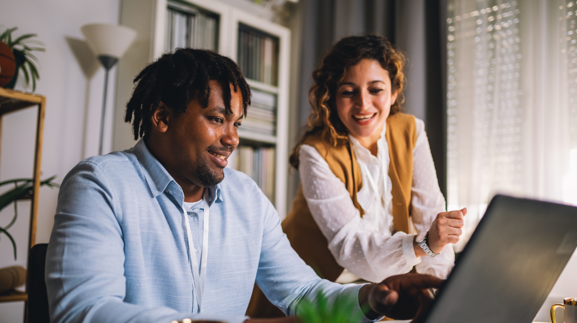 Coworkers are working together at a laptop. 