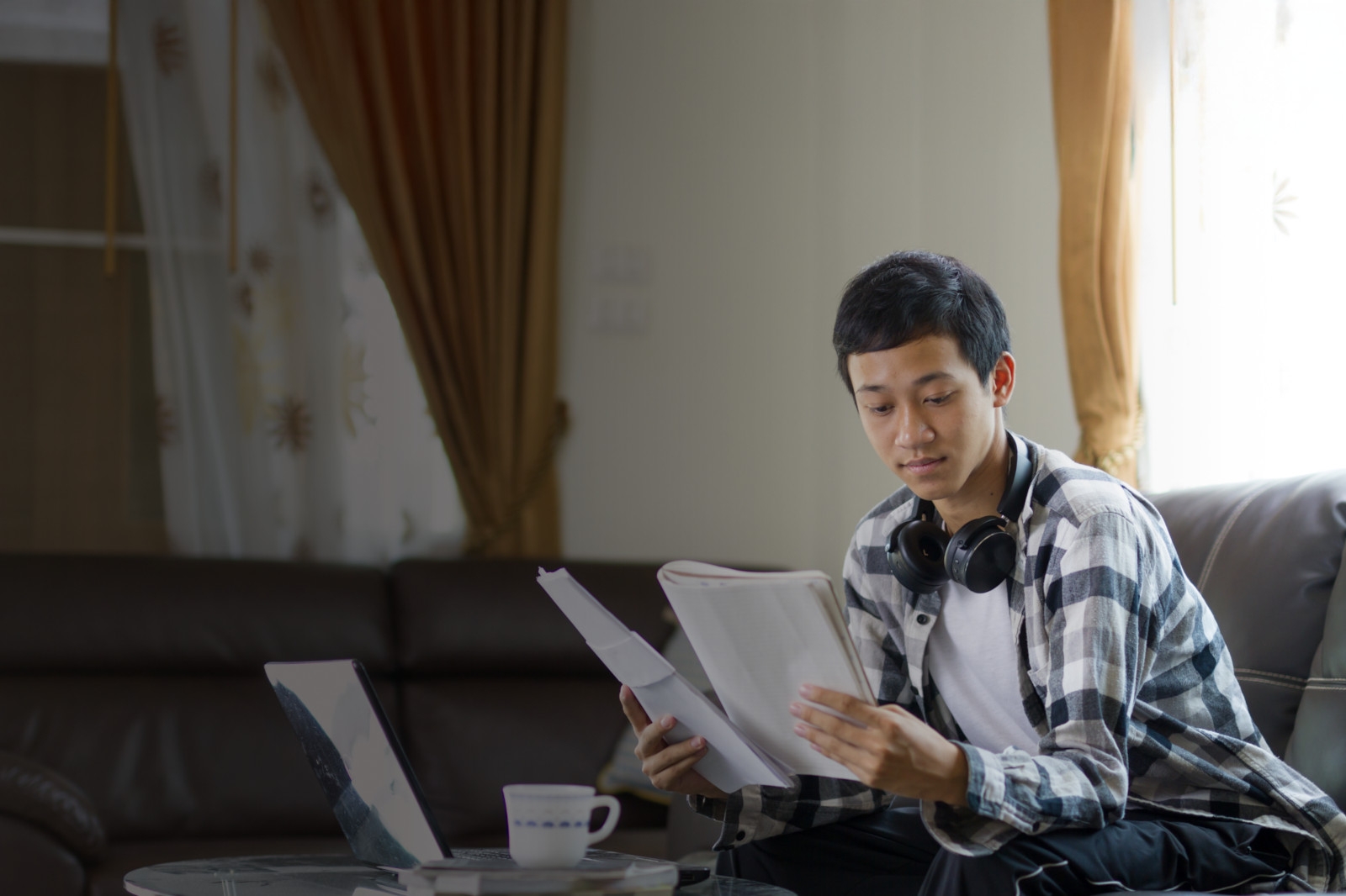 A young man is on his laptop reviewing paperwork.
