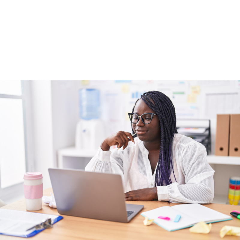 A woman is at her desk working on her laptop.